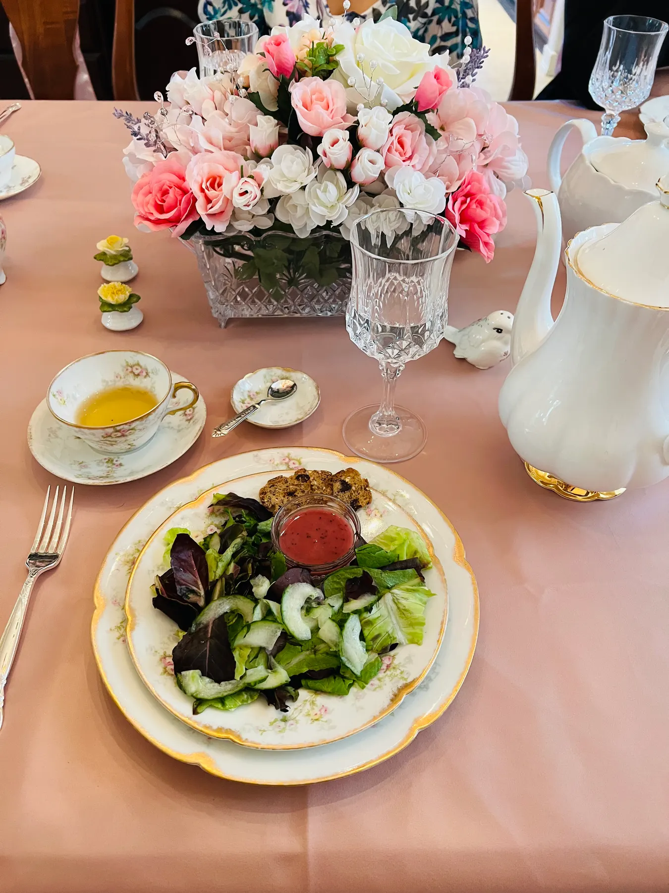 Place setting with fresh roses, gold-rimmed floral china and a plated gluten-free lunch