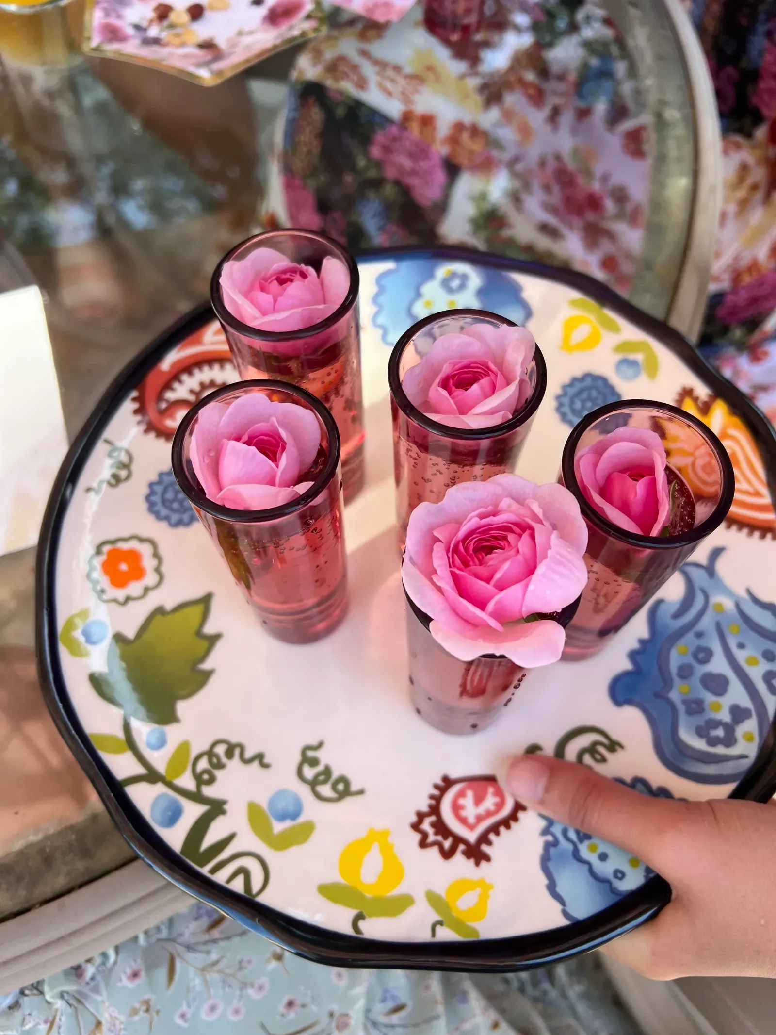 Tray of party drinks garnished with fresh pink roses on hand-painted floral china